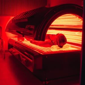 Woman lying down in a state-of-the-art full-body red light therapy bed at Renu London