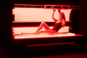 Woman in a black swimsuit entering a red light therapy bed